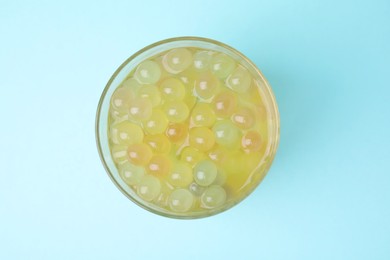 Photo of Tasty bubble tea in glass on light blue background, top view