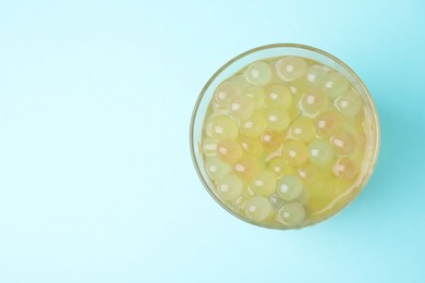 Photo of Tasty bubble tea in glass on light blue background, top view. Space for text