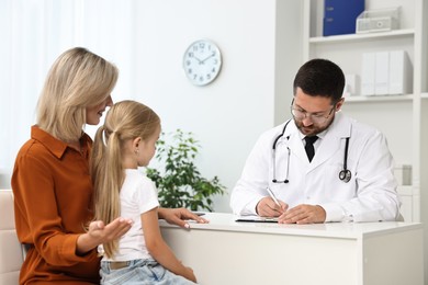 Photo of Doctor consulting little girl and her mother in hospital