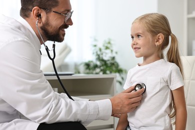 Doctor examining little girl with stethoscope in hospital