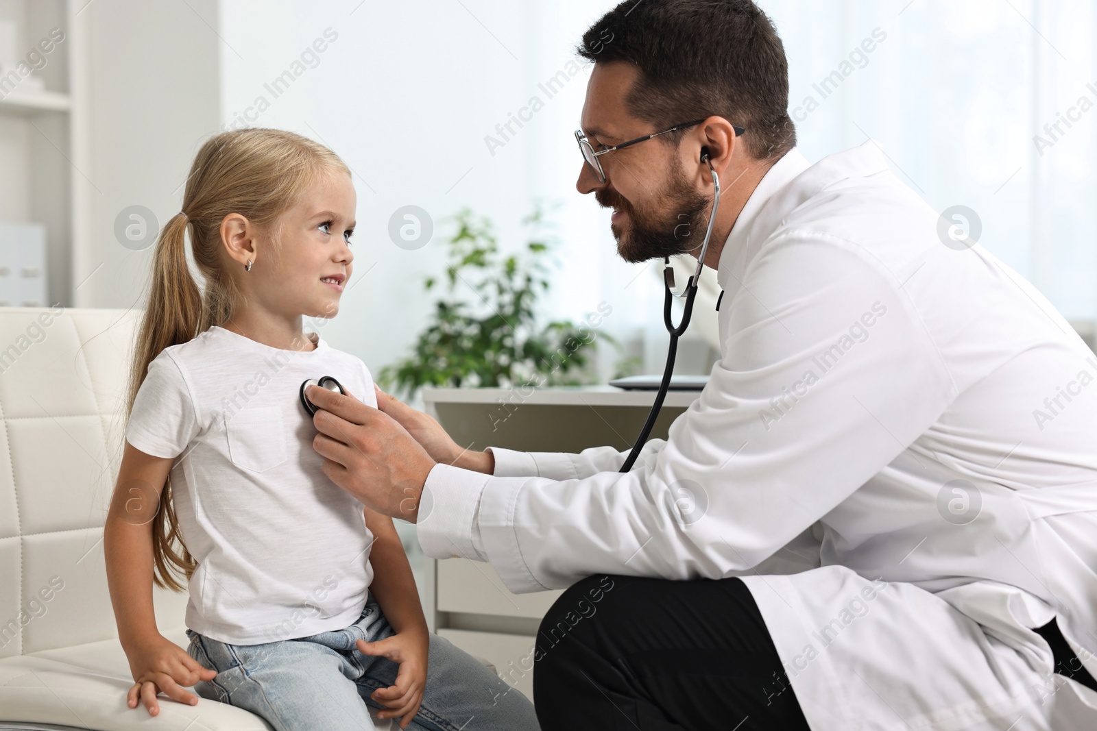 Photo of Doctor examining little girl with stethoscope in hospital