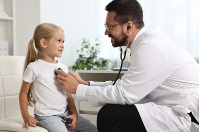 Photo of Doctor examining little girl with stethoscope in hospital