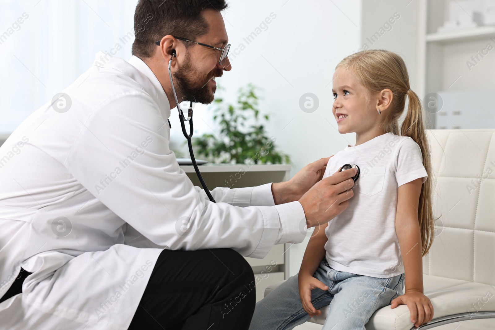 Photo of Doctor examining little girl with stethoscope in hospital