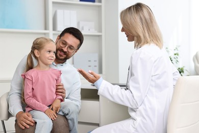 Doctor consulting little girl and her father in hospital