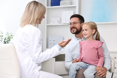 Doctor consulting little girl and her father in hospital