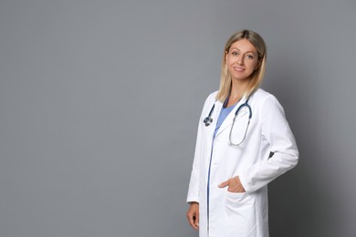 Portrait of doctor in medical uniform with stethoscope on grey background, space for text