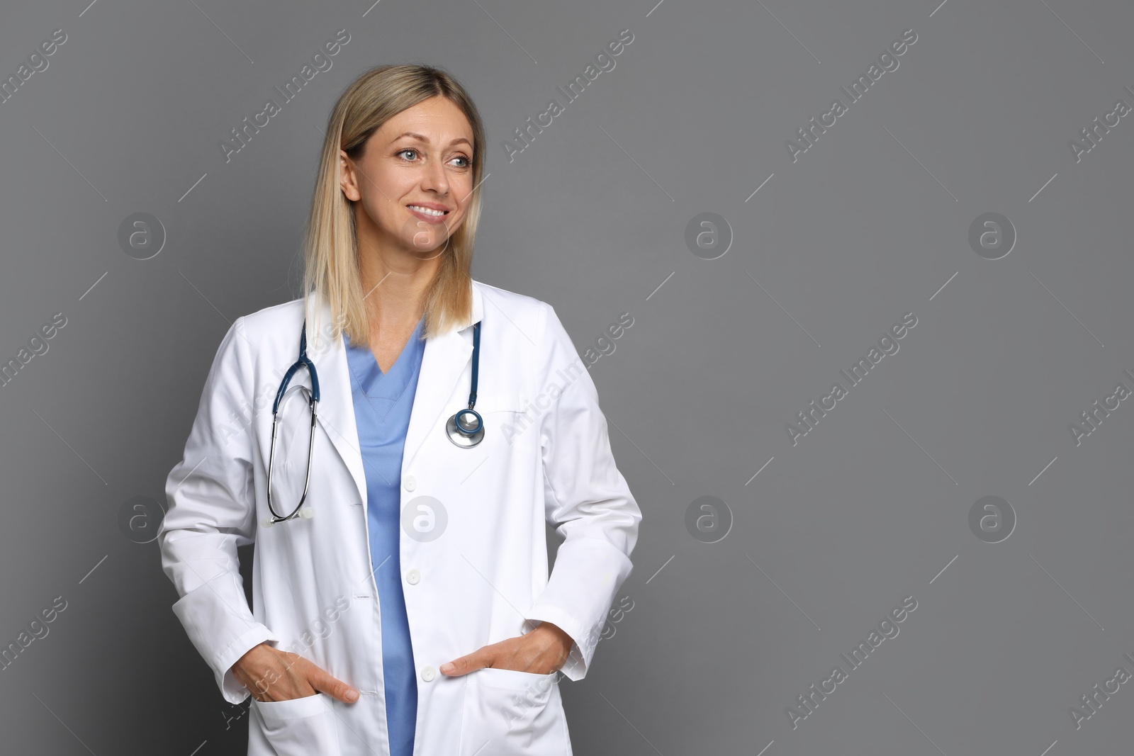 Photo of Portrait of doctor in medical uniform with stethoscope on grey background, space for text