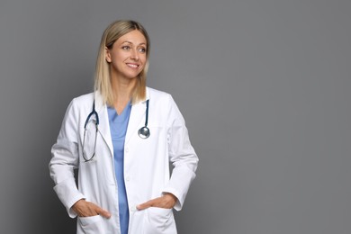 Portrait of doctor in medical uniform with stethoscope on grey background, space for text