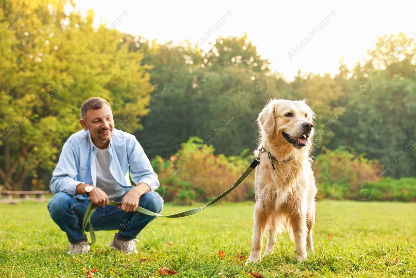 Photo of Smiling man with cute Golden Retriever dog on spring day