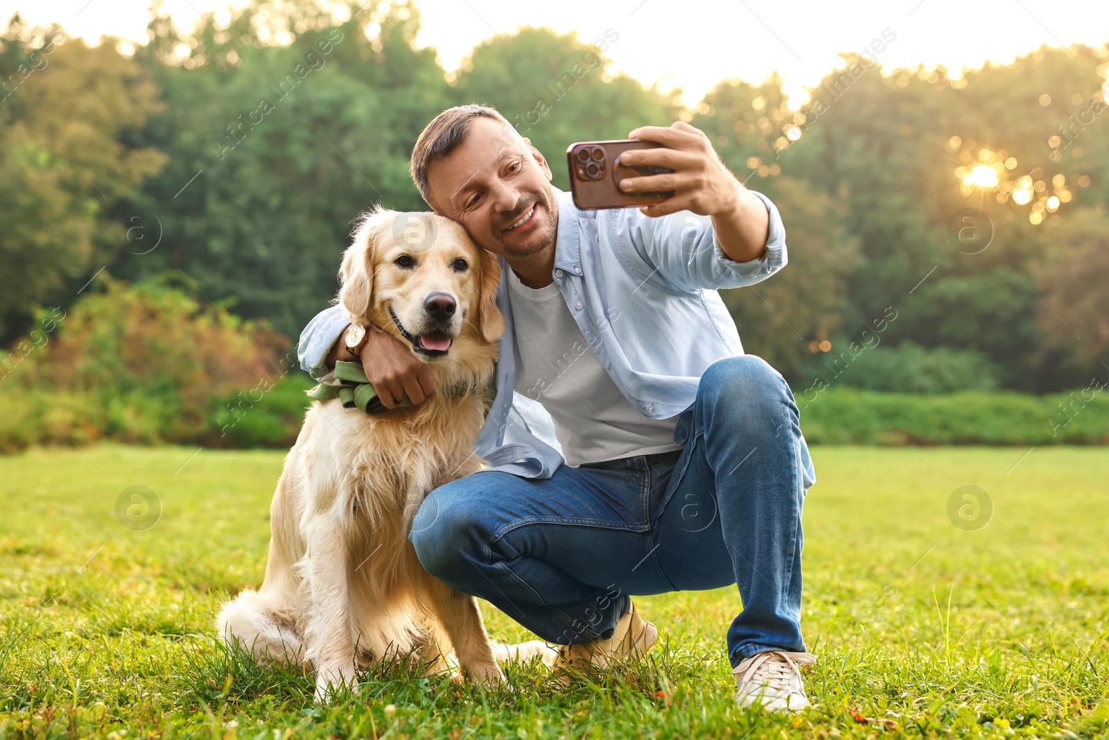 Photo of Smiling man with cute Golden Retriever dog taking selfie on spring day