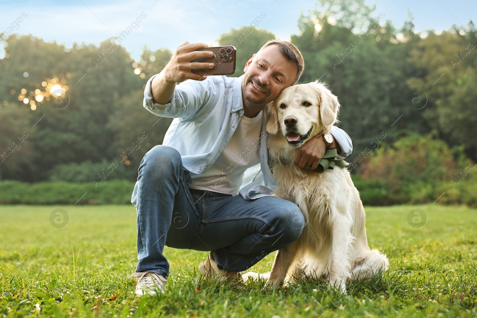 Photo of Smiling man with cute Golden Retriever dog taking selfie on spring day