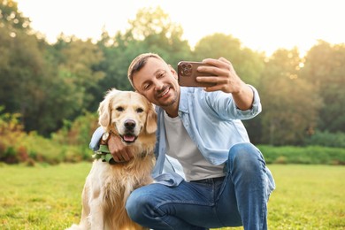 Photo of Smiling man with cute Golden Retriever dog taking selfie on spring day