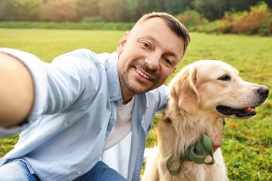 Photo of Smiling man with cute Golden Retriever dog taking selfie on spring day