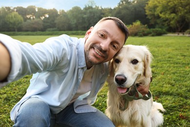 Smiling man with cute Golden Retriever dog taking selfie on spring day