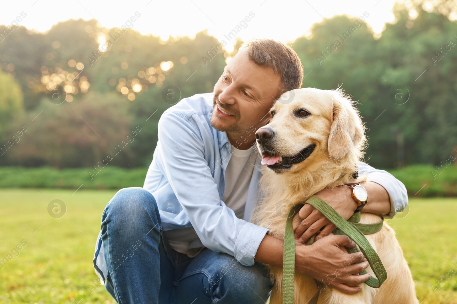 Photo of Smiling man with cute Golden Retriever dog on spring day