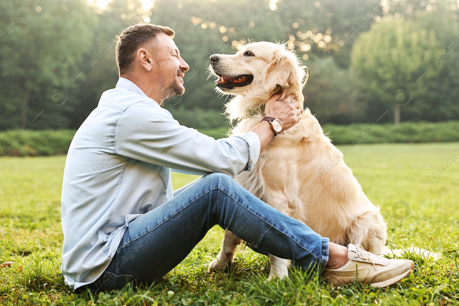 Photo of Smiling man with cute Golden Retriever dog on spring day