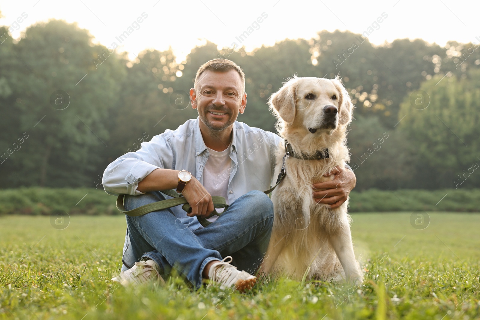 Photo of Smiling man with cute Golden Retriever dog on spring day