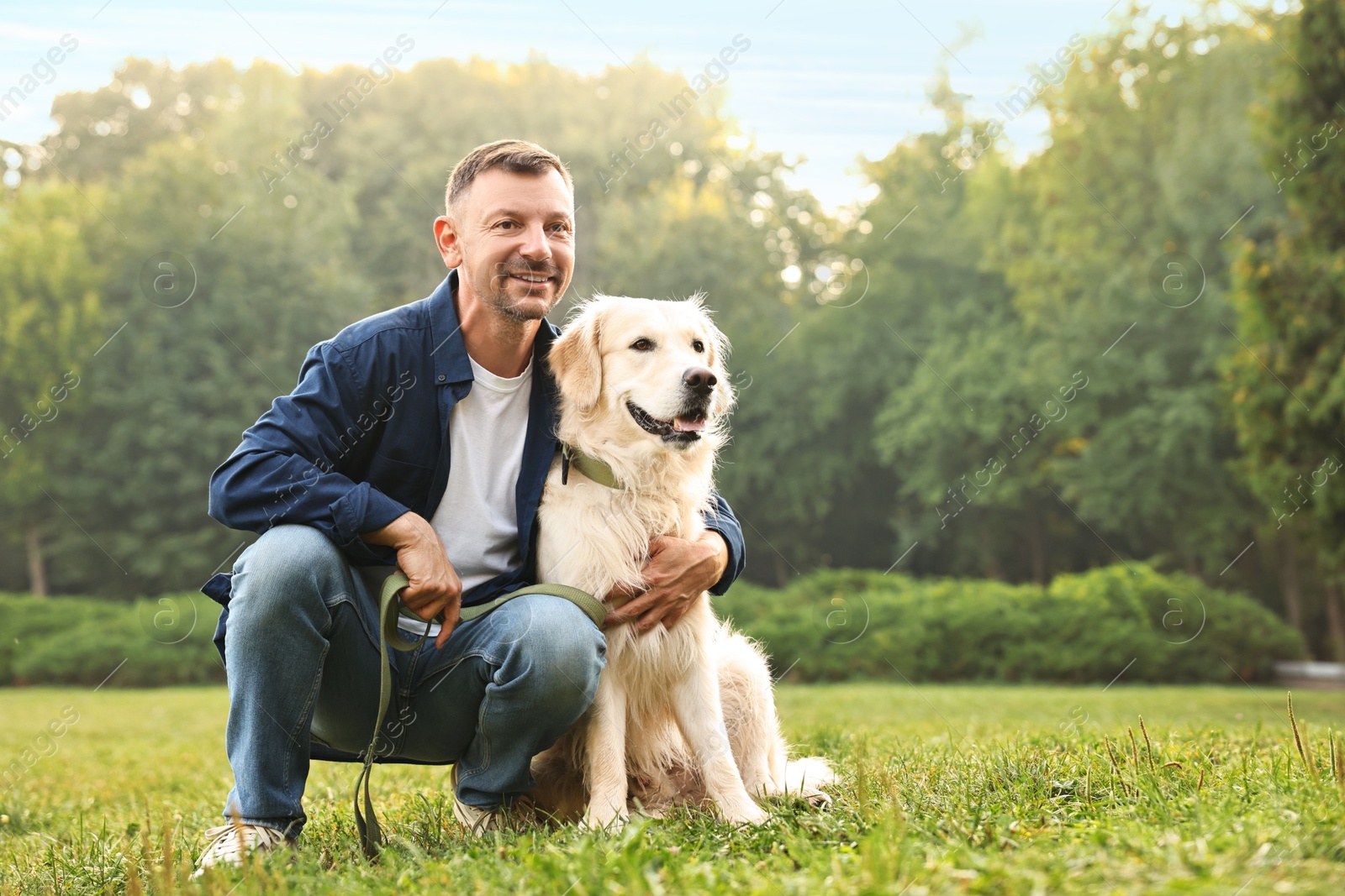 Photo of Smiling man with cute Golden Retriever dog on spring day, space for text