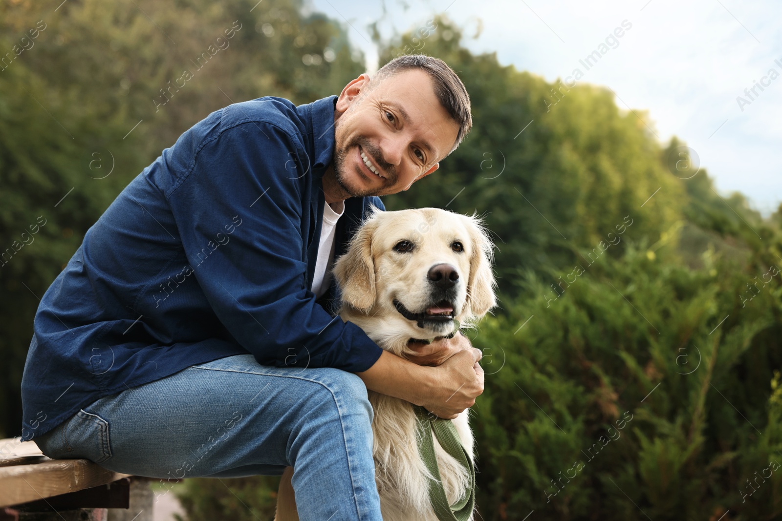 Photo of Smiling man with cute Golden Retriever dog on spring day