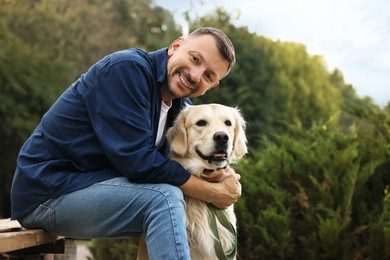 Smiling man with cute Golden Retriever dog on spring day