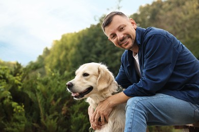 Smiling man with cute Golden Retriever dog on spring day