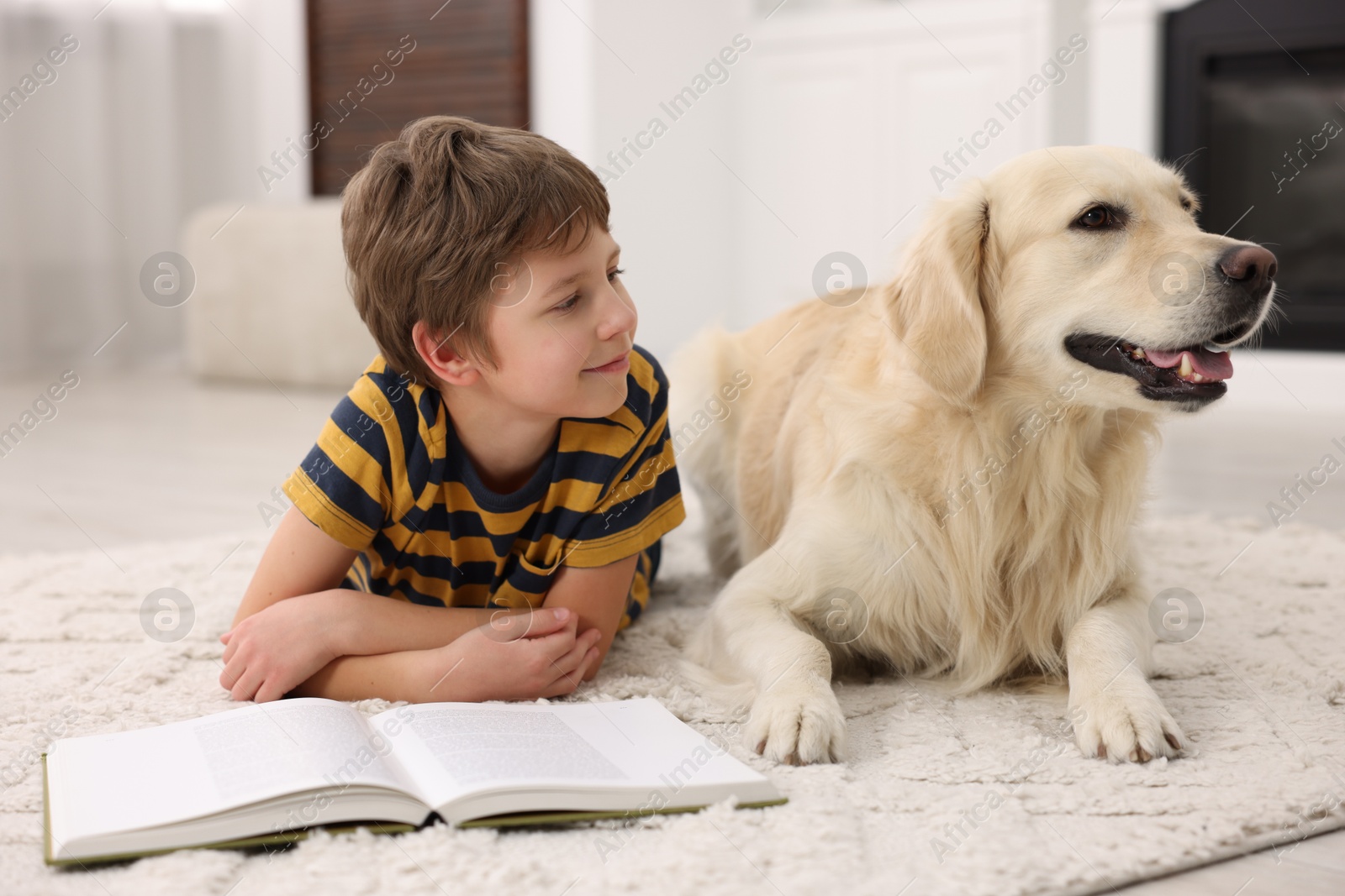 Photo of Boy reading book with his cute dog at home