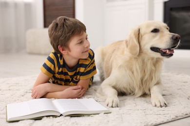 Boy reading book with his cute dog at home