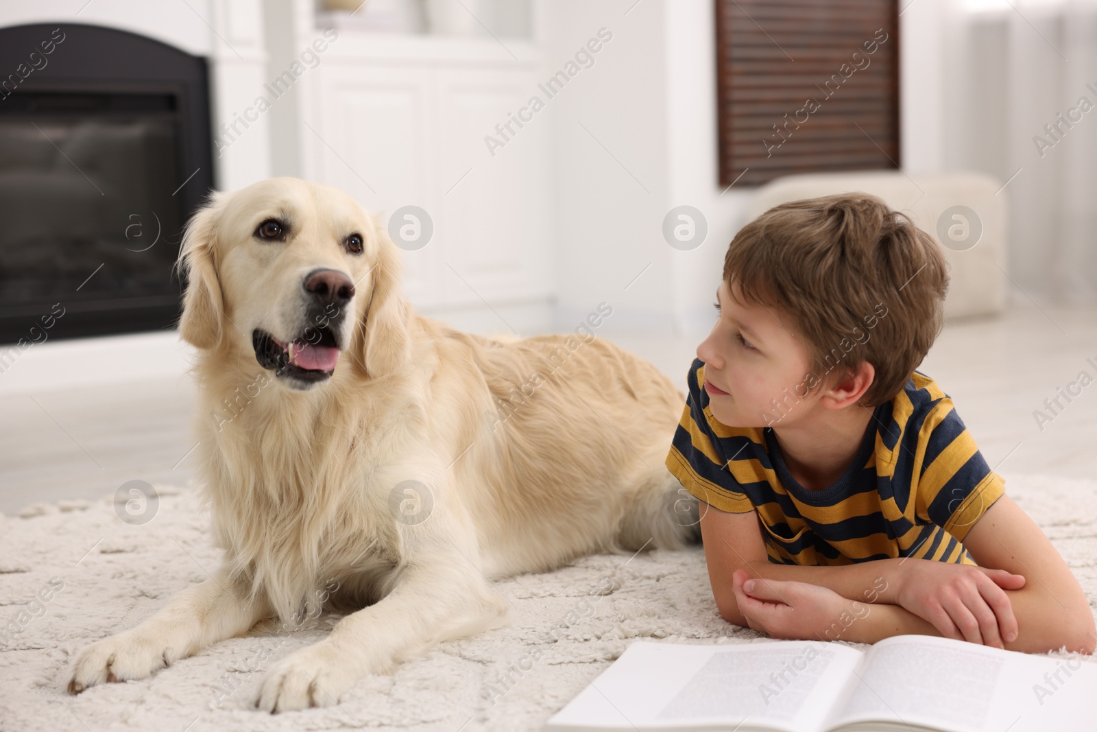 Photo of Boy reading book with his cute dog at home