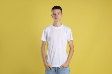 Photo of Teenage boy wearing white t-shirt on yellow background