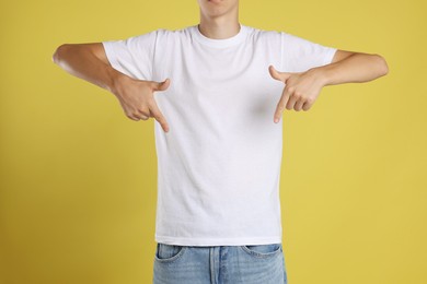 Photo of Teenage boy wearing white t-shirt on yellow background, closeup