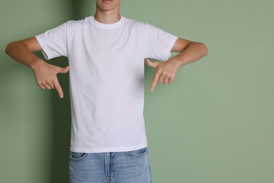 Teenage boy wearing white t-shirt on green background, closeup