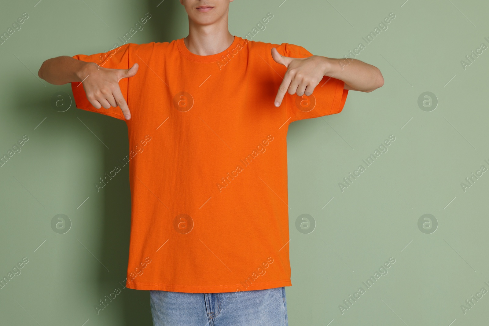 Photo of Teenage boy wearing orange t-shirt on green background, closeup