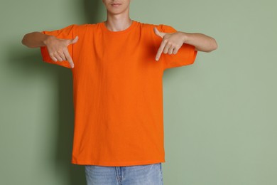 Photo of Teenage boy wearing orange t-shirt on green background, closeup