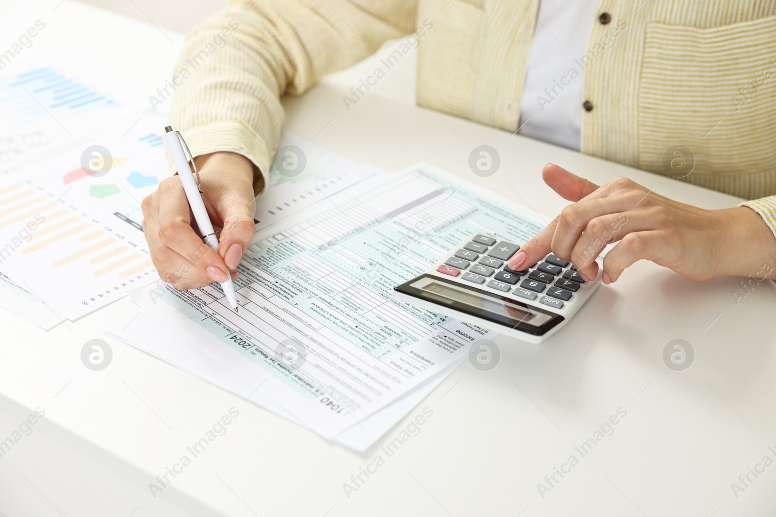 Photo of Budget planning. Woman with papers using calculator at white table, closeup