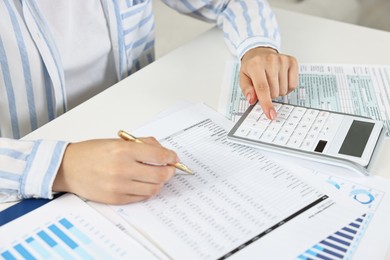 Budget planning. Woman with papers and calculator at white table, closeup