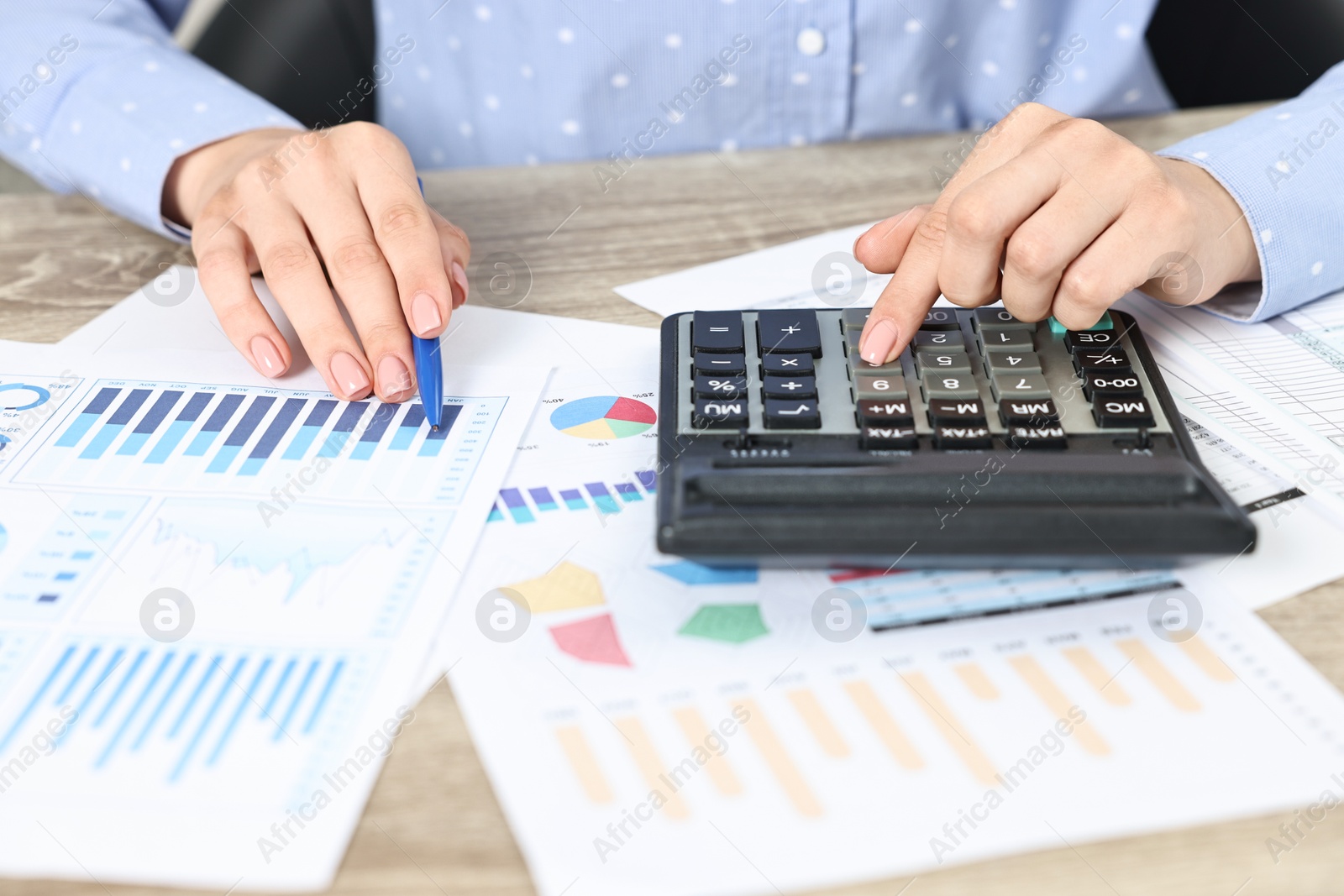 Photo of Budget planning. Woman with papers using calculator at wooden table, closeup