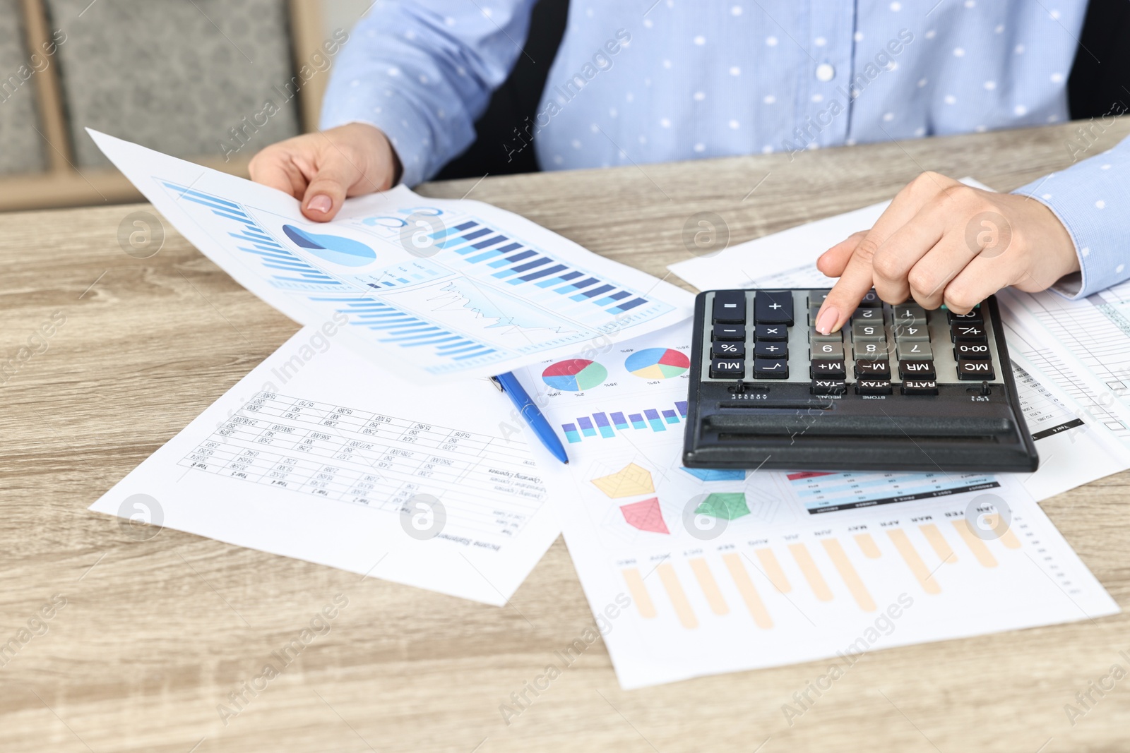 Photo of Budget planning. Woman with papers using calculator at wooden table, closeup