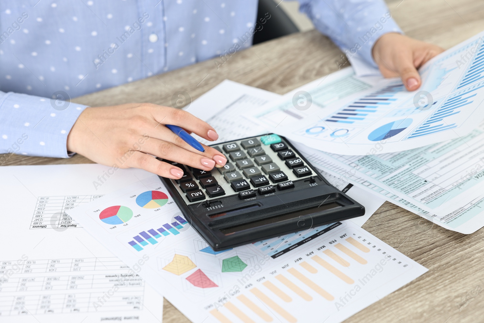 Photo of Budget planning. Woman with papers and calculator at wooden table, closeup