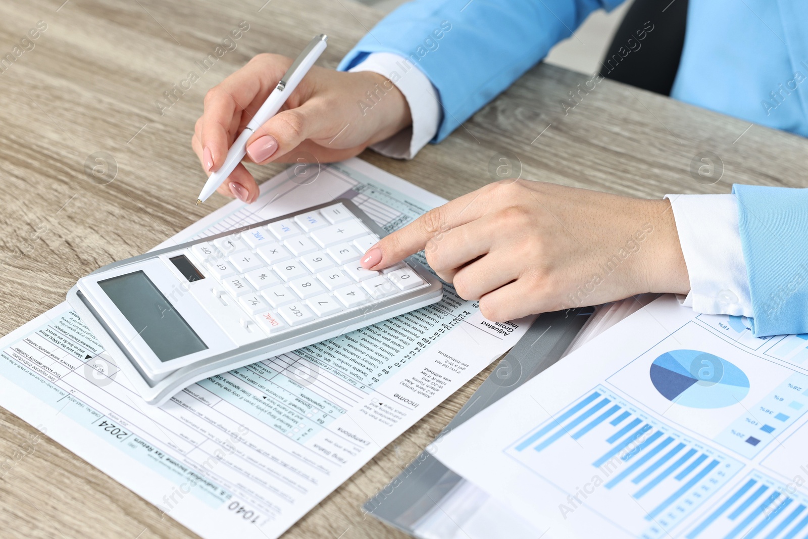 Photo of Budget planning. Woman with papers and calculator at wooden table, closeup