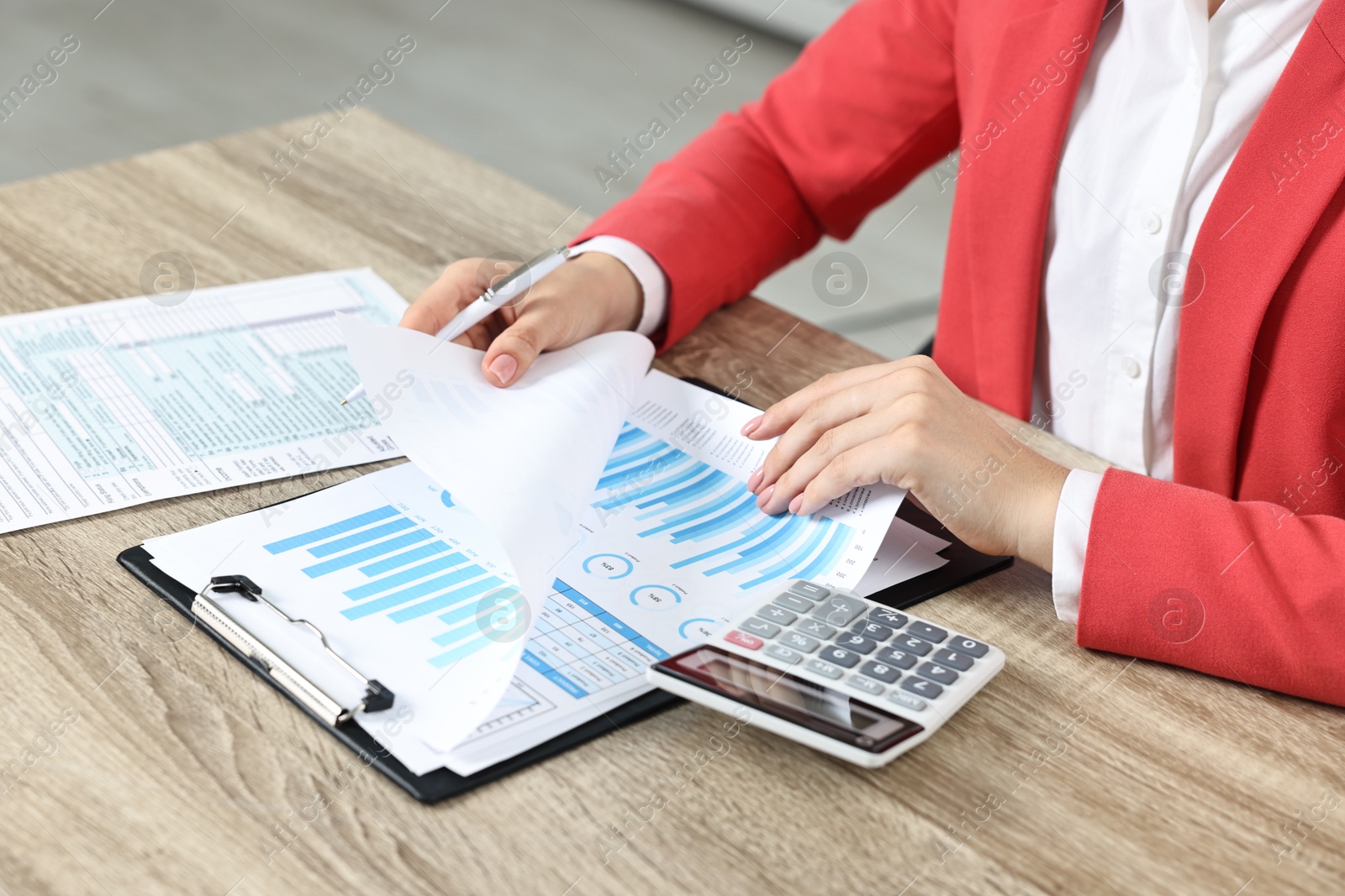 Photo of Budget planning. Woman with papers and calculator at wooden table, closeup