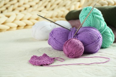 Photo of Bright yarns, pattern sample and knitting needles on soft blanket