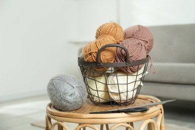 Photo of Skeins of soft yarn, knitting needles and scissors on table indoors