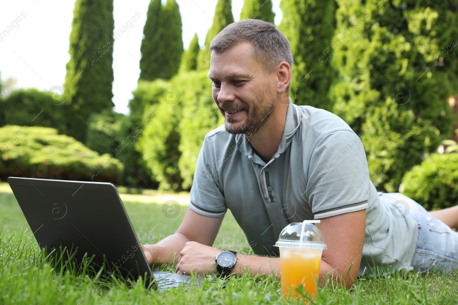 Photo of Man using laptop on green lawn outdoors