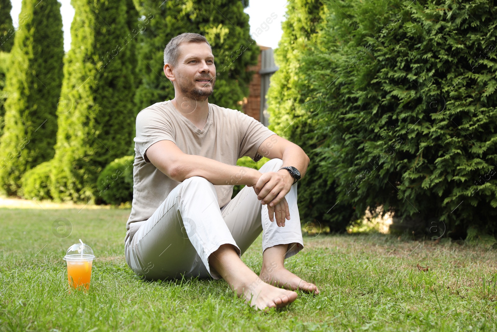 Photo of Handsome man sitting on green lawn outdoors