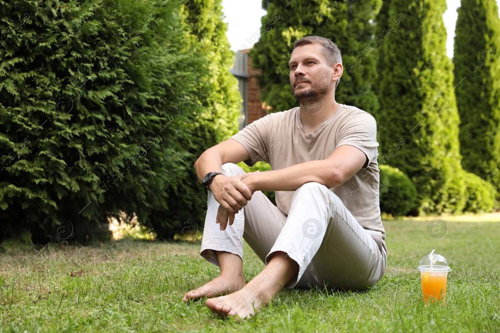 Photo of Handsome man sitting on green lawn outdoors