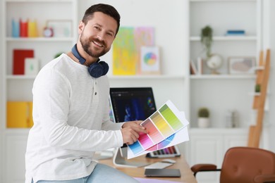 Smiling designer with color palette in office