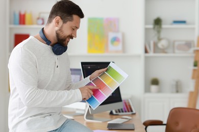 Smiling designer with color palette in office