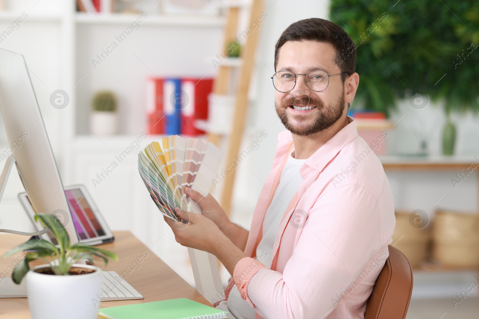 Photo of Designer working with color samples at table in office