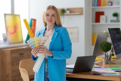 Photo of Young designer with color samples in office