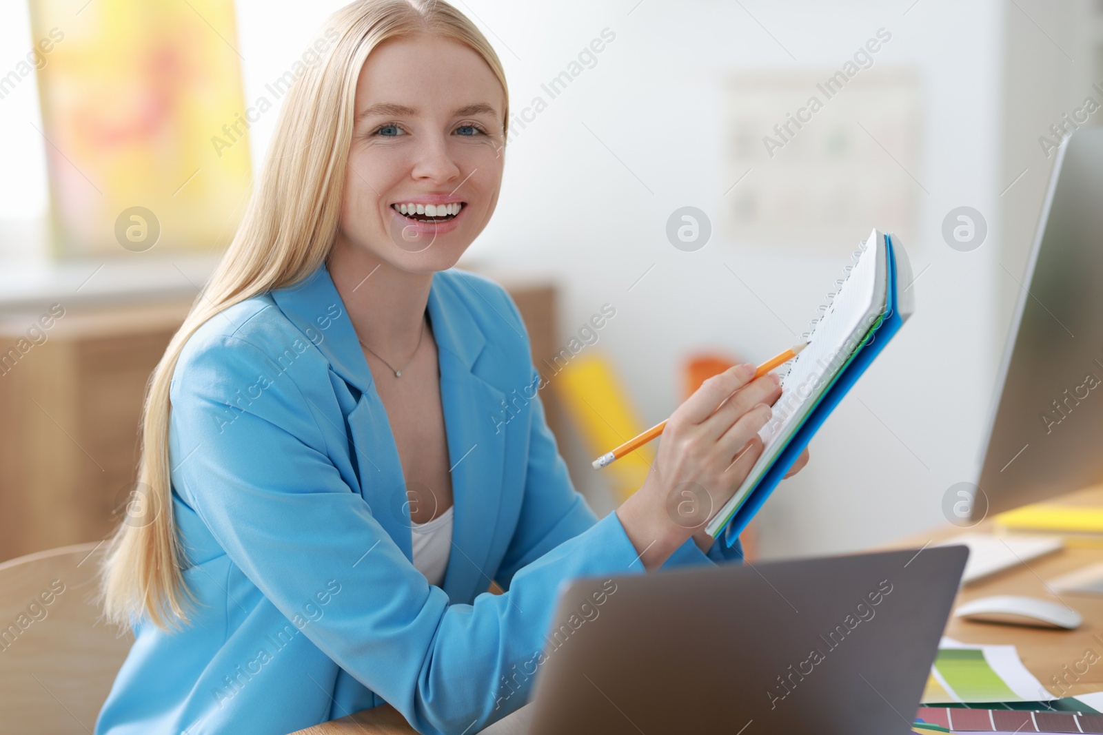 Photo of Designer with notebook and laptop working at table in office